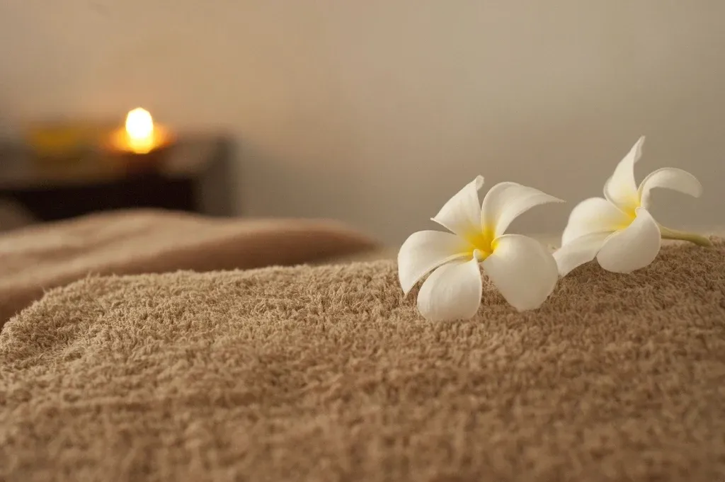 A white frangipani flower on a soft towel by candlelight