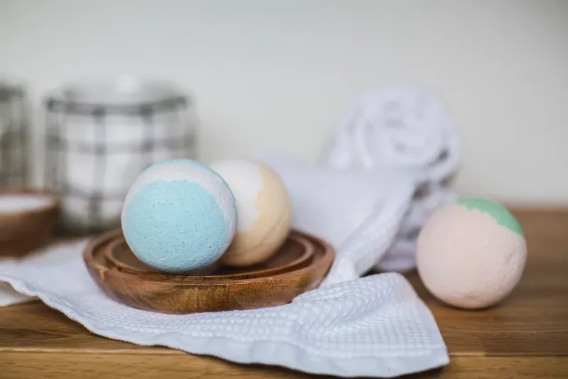 Three pastel bath bombs on a wooden tray
